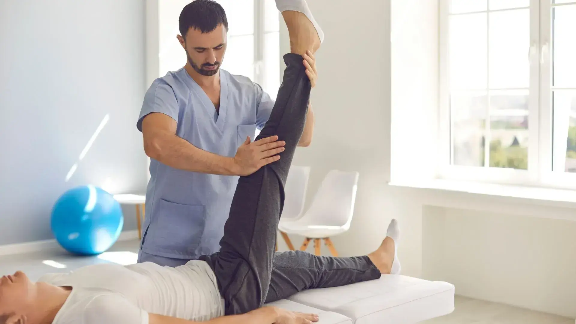 Woman performing yoga backbend stretch exercise during home physiotherapy session with trainer